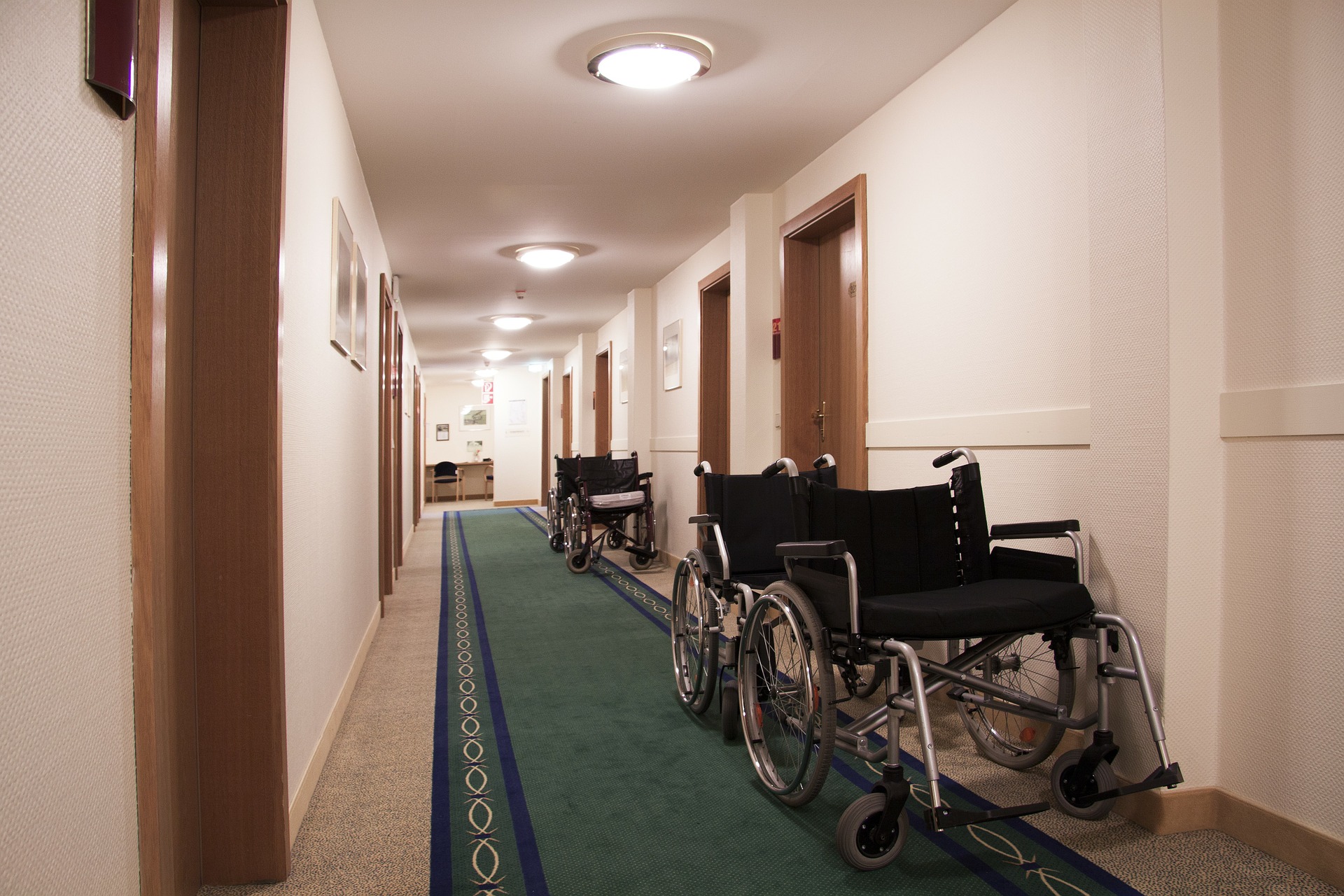 Symbolbild Rehabilitation (langer Einrichtungsflur mit leeren Rollstühlen vor der Tür)